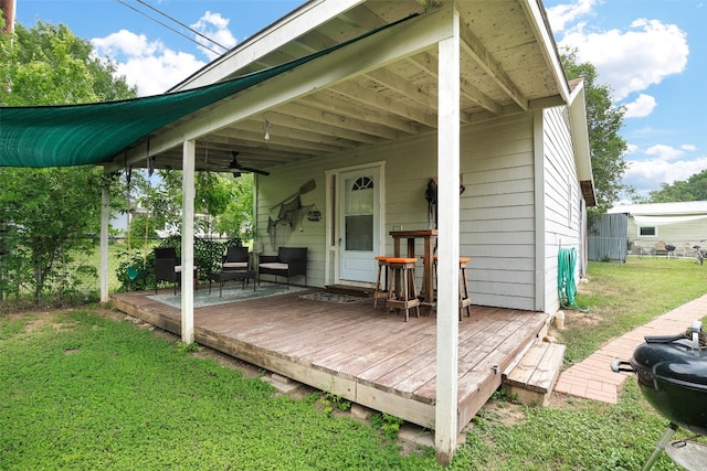 wooden deck with a yard and ceiling fan