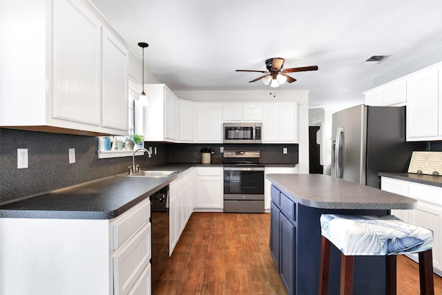 kitchen featuring sink, a kitchen island, white cabinetry, stainless steel appliances, and dark hardwood / wood-style floors