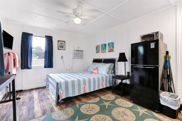 bedroom with a wall unit AC, dark wood-type flooring, ceiling fan, and black fridge