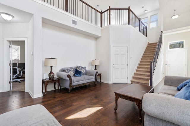 living room with a towering ceiling and dark hardwood / wood-style floors