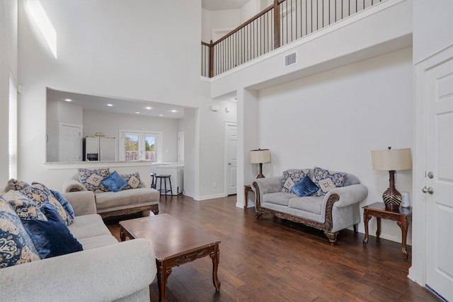 living room with a towering ceiling and dark hardwood / wood-style flooring