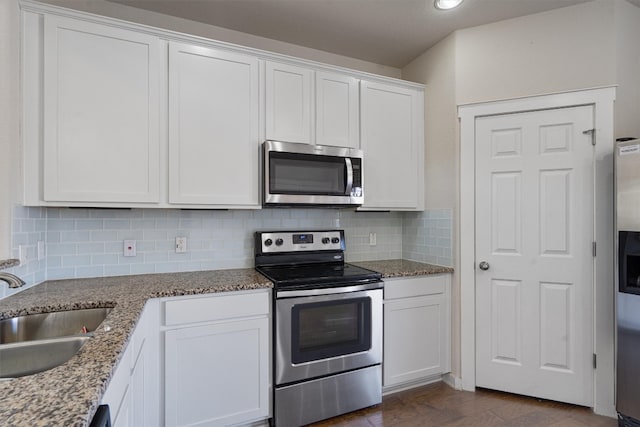 kitchen featuring appliances with stainless steel finishes, sink, white cabinets, dark wood-type flooring, and light stone counters