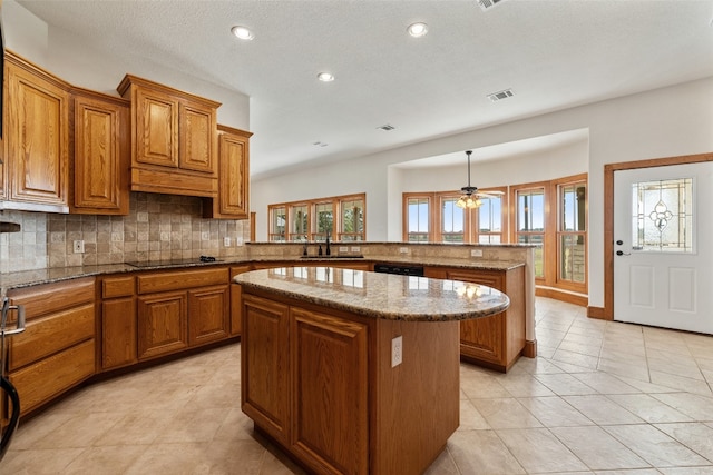 kitchen with kitchen peninsula, black electric cooktop, ceiling fan, sink, and a center island