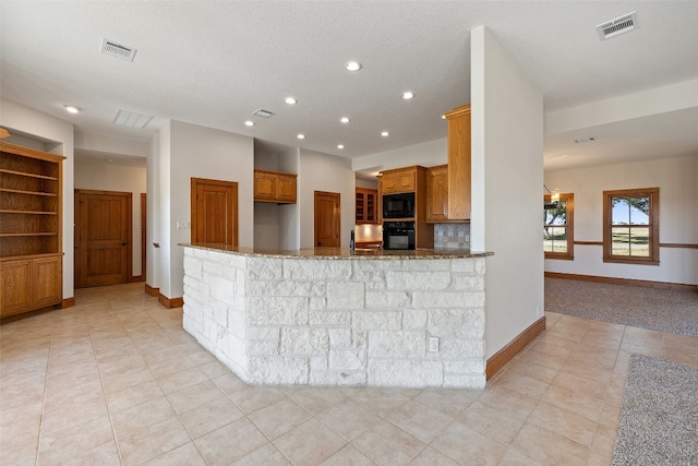 kitchen featuring stone counters, black appliances, built in features, a textured ceiling, and kitchen peninsula