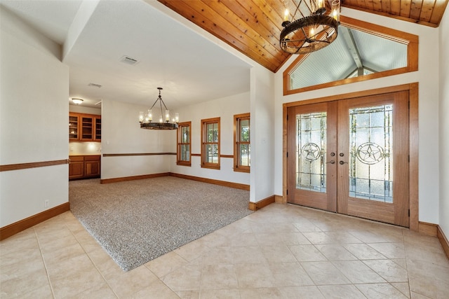 carpeted foyer featuring french doors, wooden ceiling, vaulted ceiling, and an inviting chandelier