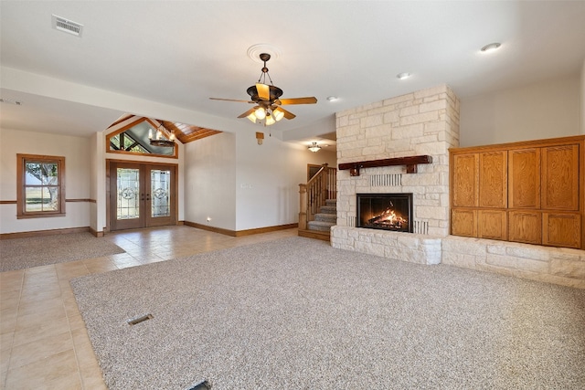 unfurnished living room featuring ceiling fan, french doors, lofted ceiling with beams, a fireplace, and light tile patterned flooring