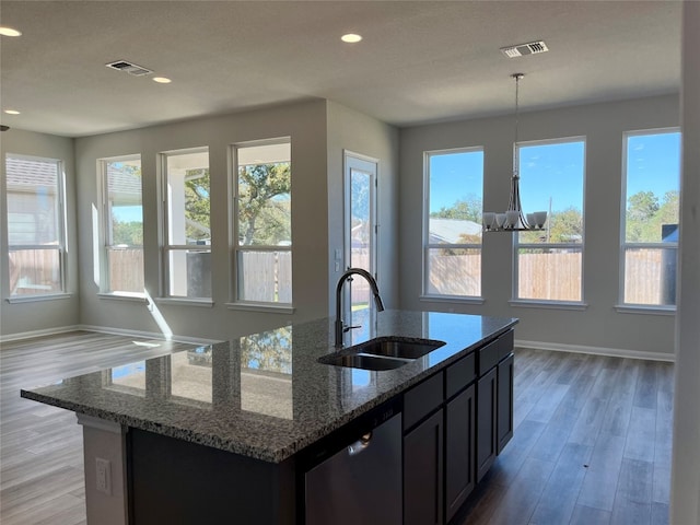 kitchen featuring dishwasher, a kitchen island with sink, sink, light hardwood / wood-style flooring, and stone countertops