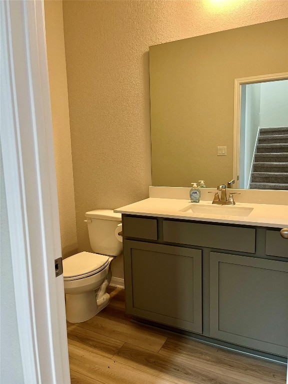 bathroom with hardwood / wood-style floors, vanity, and toilet