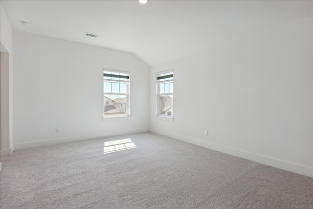 carpeted spare room with vaulted ceiling