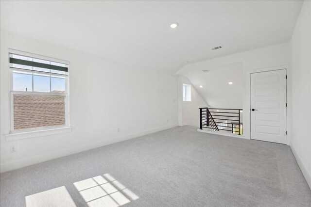 carpeted spare room featuring a healthy amount of sunlight and vaulted ceiling