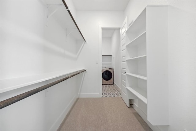 walk in closet with light colored carpet and washer / dryer