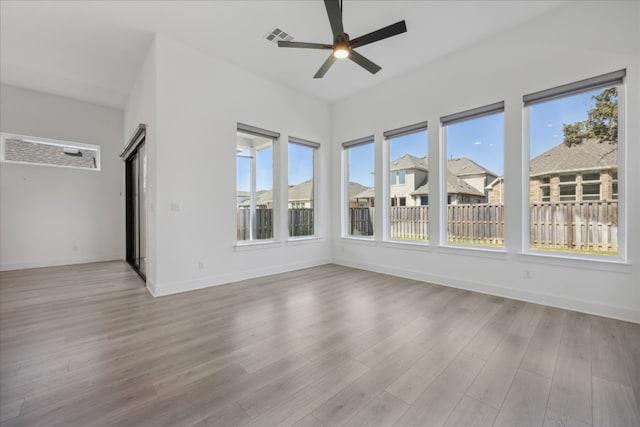 empty room featuring ceiling fan, plenty of natural light, and light wood-type flooring