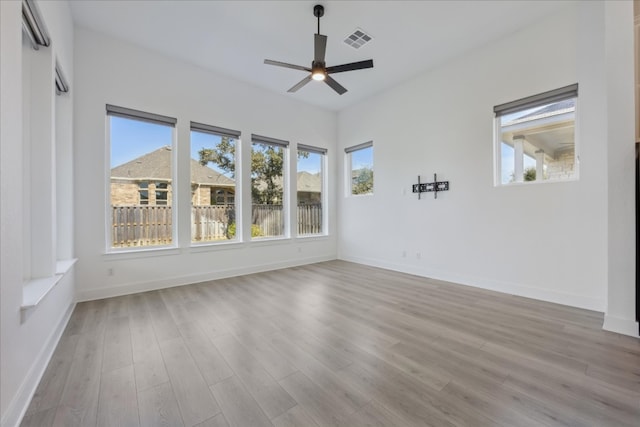 empty room featuring light hardwood / wood-style flooring, a wealth of natural light, and ceiling fan