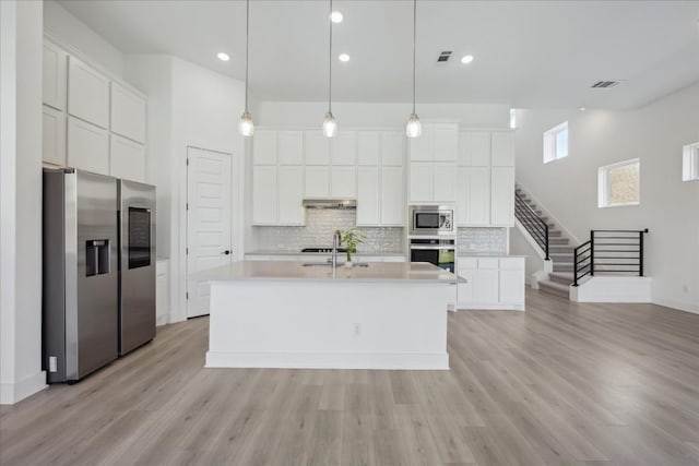 kitchen with white cabinetry, appliances with stainless steel finishes, and a kitchen island with sink