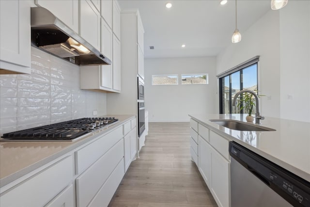 kitchen featuring appliances with stainless steel finishes, tasteful backsplash, sink, exhaust hood, and white cabinetry