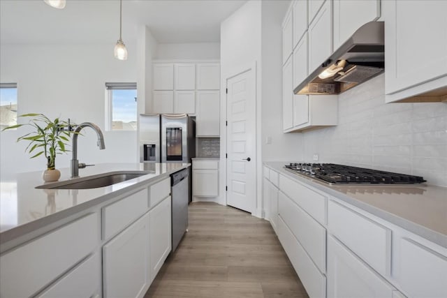 kitchen with sink, white cabinetry, hanging light fixtures, light wood-type flooring, and stainless steel appliances