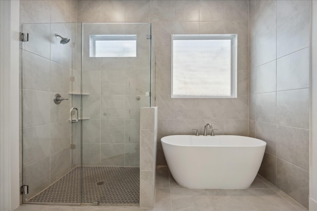 bathroom with tile patterned floors, tile walls, and independent shower and bath