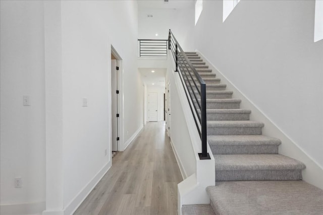 staircase featuring hardwood / wood-style floors and a towering ceiling