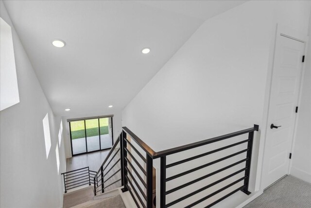 stairway featuring carpet flooring and lofted ceiling