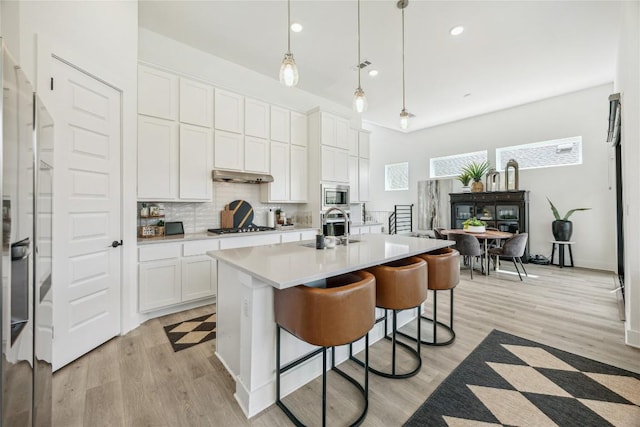 1325 Kneehigh Dr, Georgetown, TX 78633 - kitchen with stainless steel appliances, light countertops, a kitchen breakfast bar, light wood-style flooring, and recessed lighting