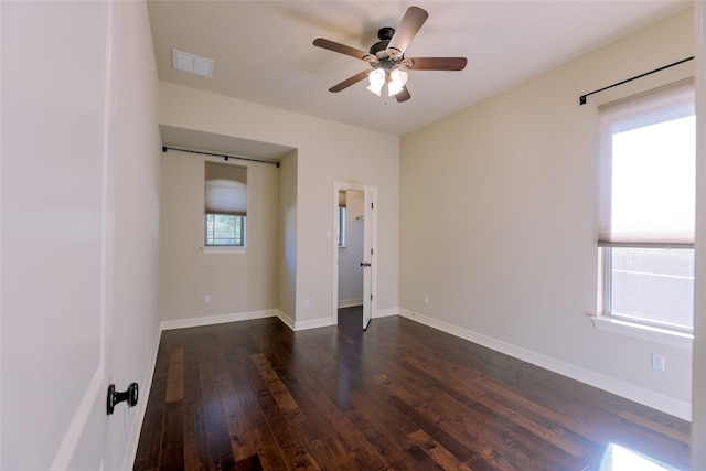 empty room featuring dark hardwood / wood-style floors, plenty of natural light, and ceiling fan