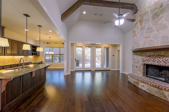 kitchen with light stone countertops, a fireplace, backsplash, dark hardwood / wood-style flooring, and beam ceiling