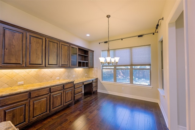 kitchen featuring dark wood-type flooring, light stone countertops, pendant lighting, a chandelier, and tasteful backsplash