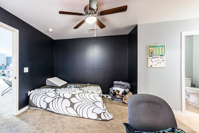 bedroom with ensuite bathroom, light colored carpet, and ceiling fan