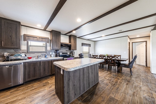 kitchen with dark hardwood / wood-style floors, a healthy amount of sunlight, appliances with stainless steel finishes, and a kitchen island