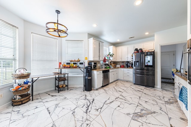 kitchen with hanging light fixtures, a notable chandelier, appliances with stainless steel finishes, and white cabinets