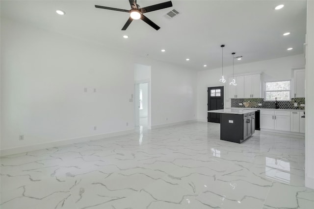 kitchen featuring sink, backsplash, a center island, white cabinets, and pendant lighting