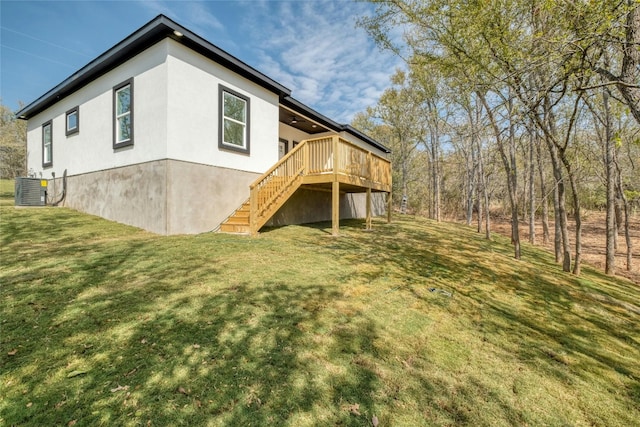 rear view of house featuring a wooden deck, central AC, and a yard