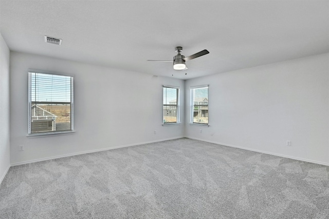 spare room featuring light colored carpet, plenty of natural light, and ceiling fan