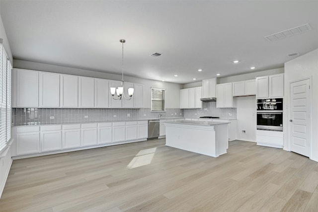 kitchen featuring white cabinets, light hardwood / wood-style flooring, a kitchen island, and hanging light fixtures