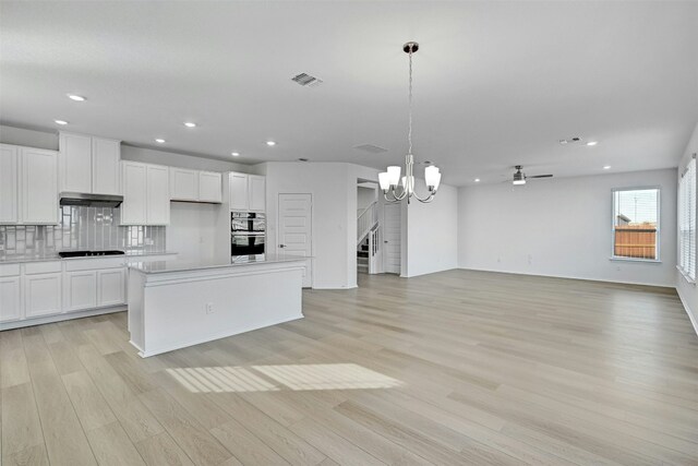 kitchen with decorative light fixtures, a center island, light wood-type flooring, and white cabinetry