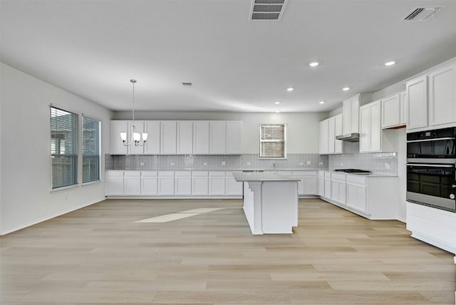 kitchen with white cabinets, decorative light fixtures, a kitchen island, and gas stovetop