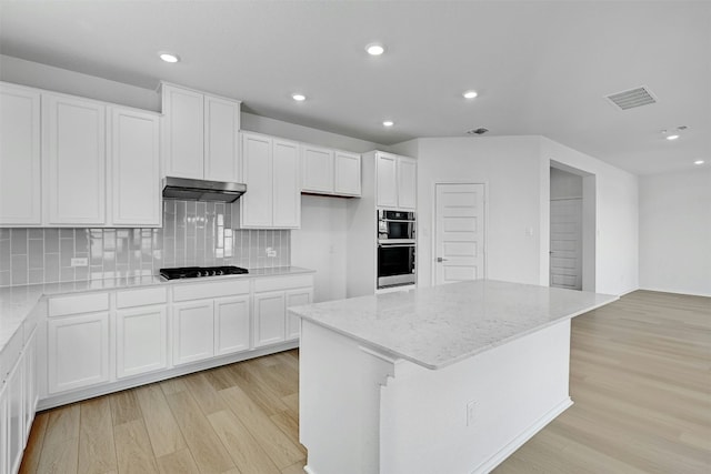 kitchen featuring black gas stovetop, stainless steel double oven, white cabinets, a center island, and light hardwood / wood-style floors