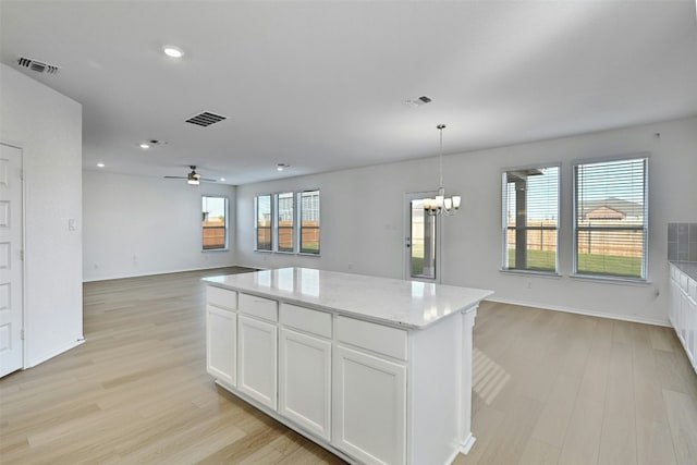 kitchen with light hardwood / wood-style floors, white cabinetry, plenty of natural light, and a kitchen island