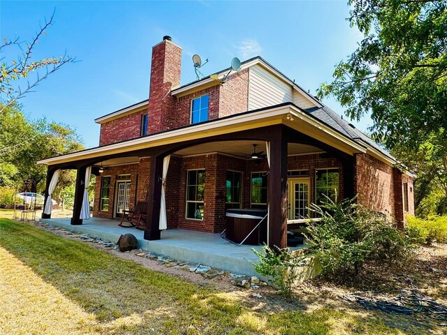 300 Copper Ln, Leander, TX 78641 - back of house with ceiling fan, brick siding, a chimney, a hot tub, and a patio