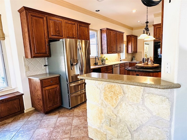 kitchen featuring kitchen peninsula, hanging light fixtures, appliances with stainless steel finishes, sink, and tasteful backsplash