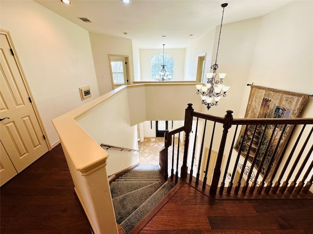 stairs featuring hardwood / wood-style floors and a notable chandelier