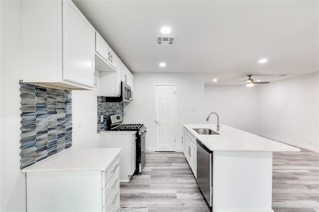 kitchen with appliances with stainless steel finishes, sink, backsplash, light hardwood / wood-style floors, and white cabinets