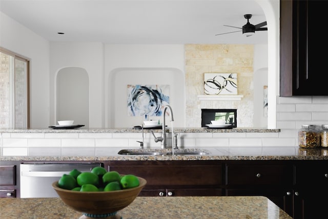 kitchen with sink, light stone countertops, tasteful backsplash, stainless steel dishwasher, and ceiling fan