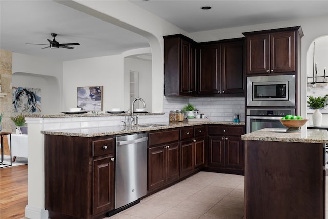 kitchen featuring a kitchen island, stainless steel appliances, backsplash, sink, and dark brown cabinetry