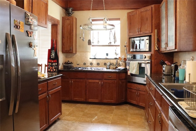 kitchen featuring backsplash, appliances with stainless steel finishes, an inviting chandelier, and pendant lighting