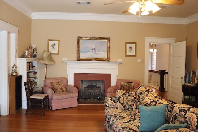 living area with ornamental molding, wood-type flooring, and ceiling fan