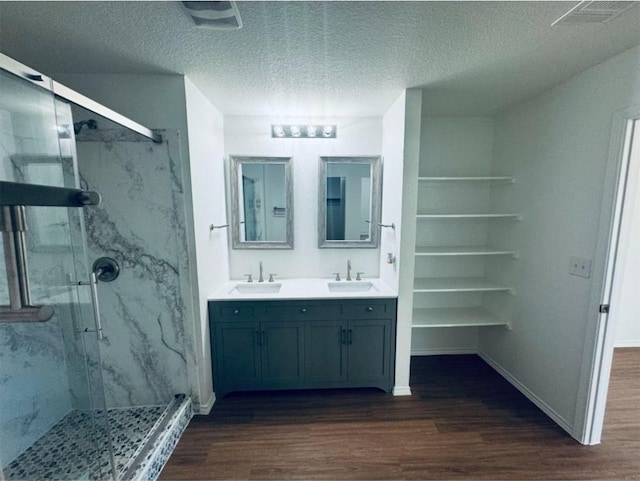 bathroom with vanity, wood-type flooring, a textured ceiling, and a shower with door