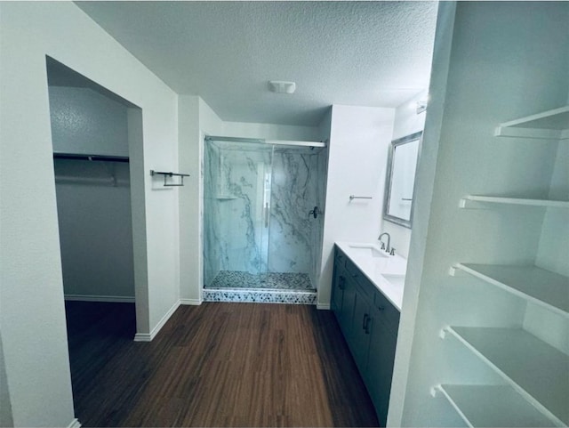 bathroom with hardwood / wood-style floors, vanity, a shower with shower door, and a textured ceiling