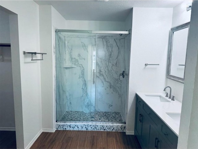 bathroom featuring wood-type flooring, vanity, a textured ceiling, and an enclosed shower