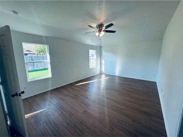 spare room featuring plenty of natural light, dark wood-type flooring, and a textured ceiling